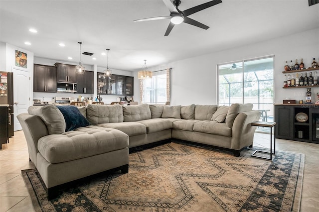 tiled living room featuring ceiling fan, a healthy amount of sunlight, and bar area