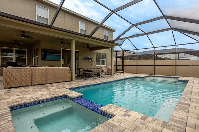 view of pool featuring glass enclosure, an in ground hot tub, ceiling fan, an outdoor living space, and a patio