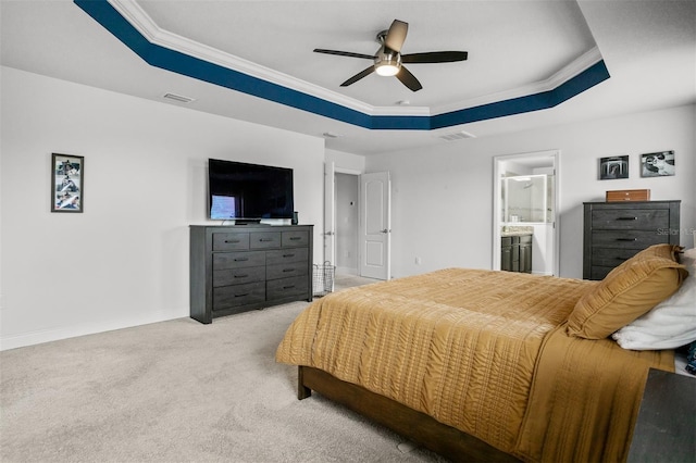 carpeted bedroom with connected bathroom, a tray ceiling, ornamental molding, and ceiling fan