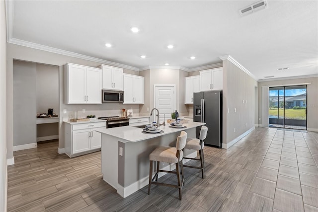 kitchen featuring sink, a breakfast bar area, appliances with stainless steel finishes, white cabinetry, and an island with sink