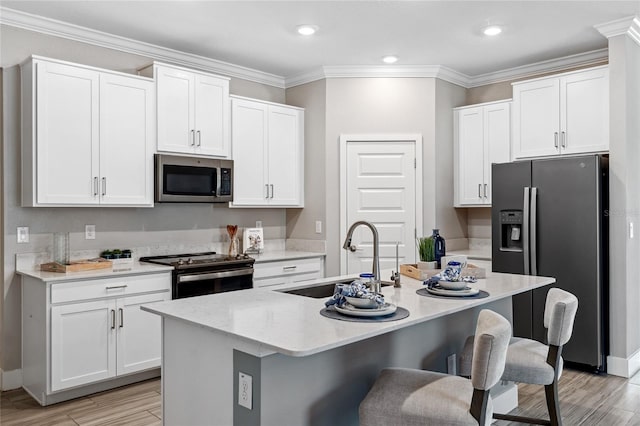 kitchen featuring a kitchen island with sink, white cabinetry, and stainless steel appliances