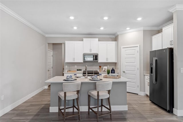 kitchen featuring appliances with stainless steel finishes, a kitchen breakfast bar, an island with sink, and white cabinets