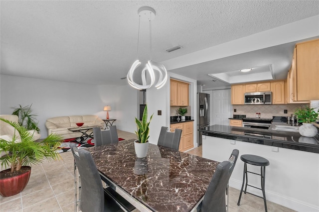 dining space featuring light tile patterned floors, a textured ceiling, and a tray ceiling