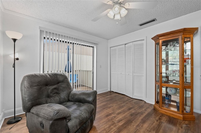 living area with ceiling fan, dark hardwood / wood-style flooring, and a textured ceiling