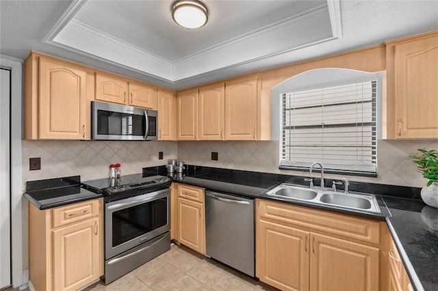 kitchen with light brown cabinetry, sink, appliances with stainless steel finishes, a tray ceiling, and backsplash