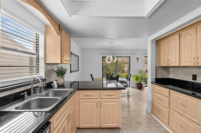 kitchen featuring sink, light tile patterned floors, light brown cabinetry, decorative light fixtures, and kitchen peninsula