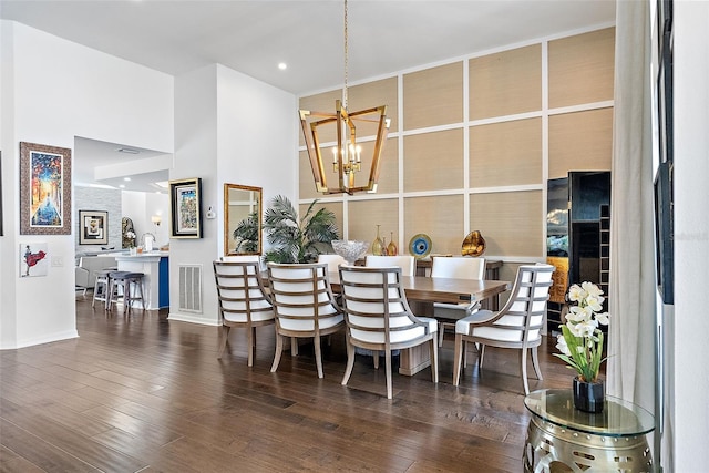 dining space with a high ceiling, a chandelier, and dark hardwood / wood-style flooring