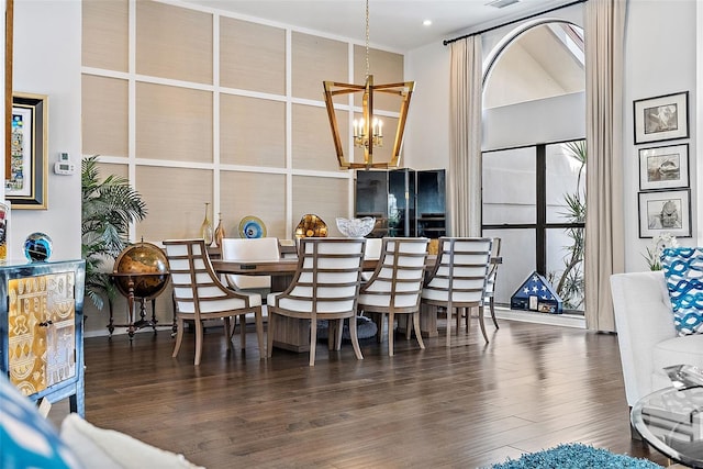 dining room featuring dark hardwood / wood-style floors, a chandelier, and a towering ceiling