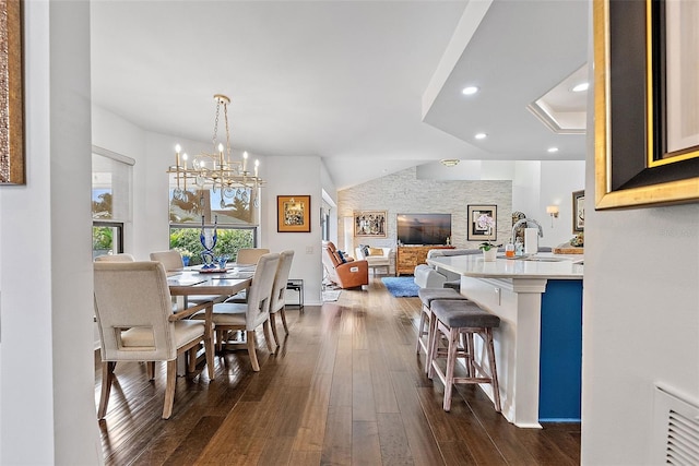 dining area featuring lofted ceiling, dark hardwood / wood-style floors, sink, and a notable chandelier