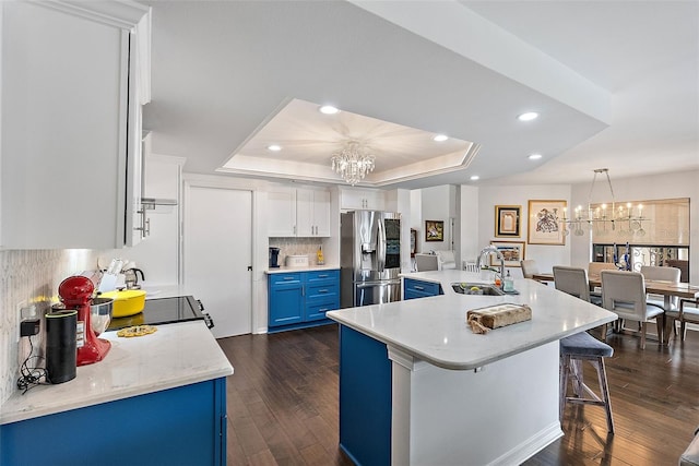 kitchen with blue cabinetry, sink, an inviting chandelier, a tray ceiling, and stainless steel fridge