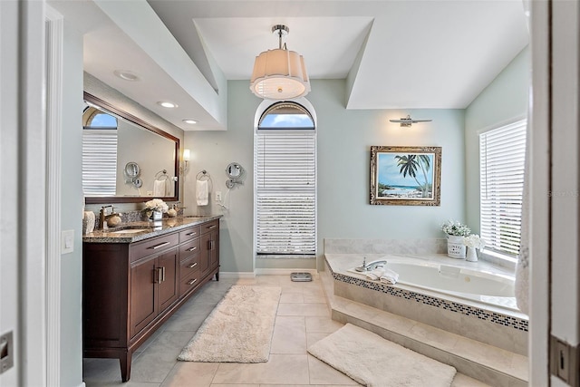 bathroom featuring a relaxing tiled tub, vanity, and tile patterned flooring