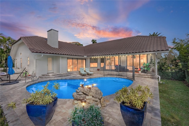 pool at dusk with a patio area