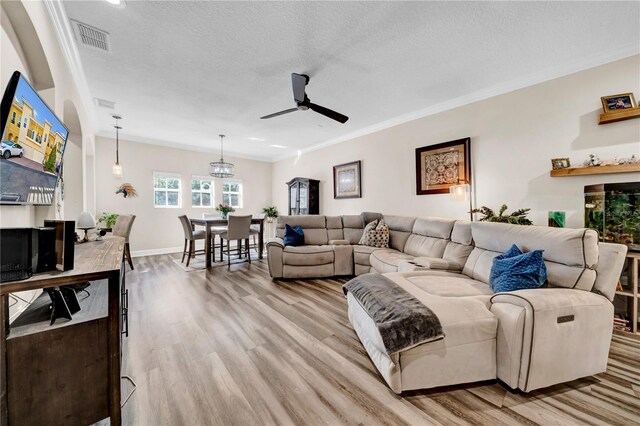 living room featuring crown molding, a textured ceiling, and light hardwood / wood-style floors