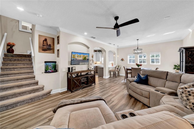 living room featuring ceiling fan, ornamental molding, light hardwood / wood-style floors, and a textured ceiling