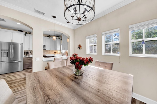 dining room featuring a notable chandelier, crown molding, light hardwood / wood-style flooring, and sink