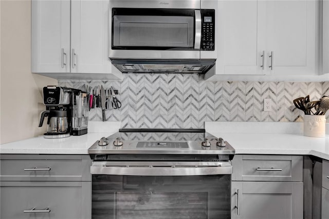 kitchen featuring white cabinets, stainless steel appliances, gray cabinets, and backsplash