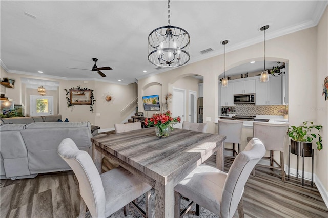 dining area with ceiling fan, ornamental molding, and wood-type flooring