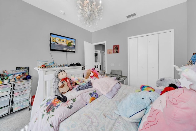 carpeted bedroom with washer / dryer, a closet, and a notable chandelier