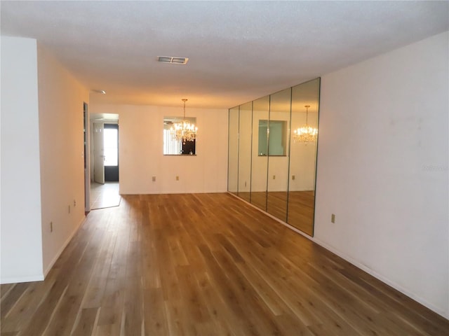 spare room with dark hardwood / wood-style flooring and a chandelier