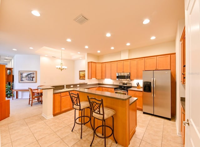 kitchen featuring a breakfast bar, hanging light fixtures, stainless steel appliances, a kitchen island, and kitchen peninsula