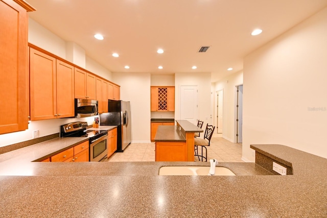 kitchen featuring appliances with stainless steel finishes, a kitchen bar, and a center island