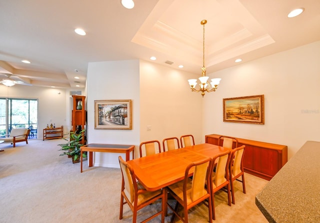 dining room featuring an inviting chandelier, a tray ceiling, light colored carpet, and crown molding