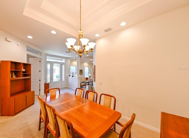 dining space with a raised ceiling, light carpet, and a notable chandelier