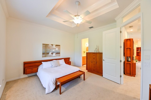 carpeted bedroom with a tray ceiling, ornamental molding, ceiling fan, and ensuite bathroom