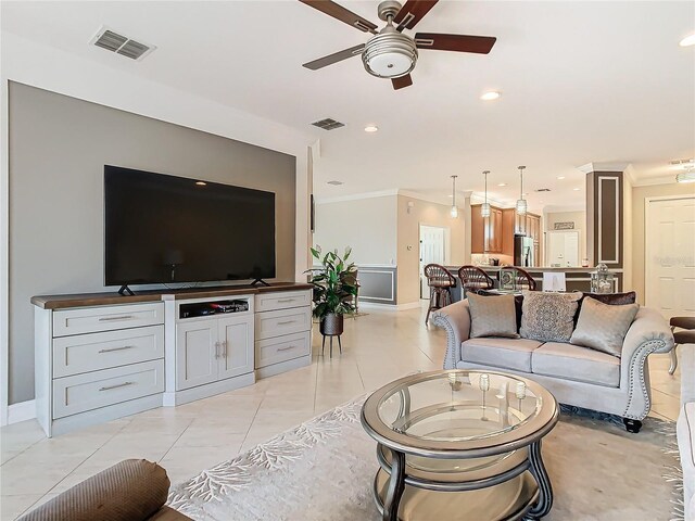 living room with light tile patterned floors, crown molding, and ceiling fan