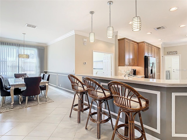 kitchen featuring ornamental molding, stainless steel fridge, and decorative light fixtures