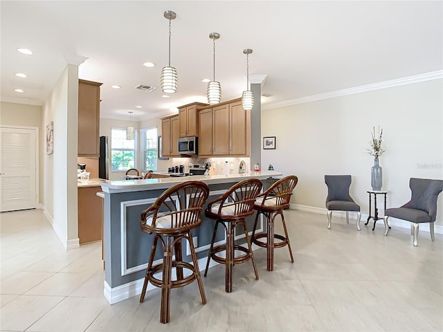 kitchen with hanging light fixtures, a kitchen breakfast bar, kitchen peninsula, stainless steel appliances, and decorative backsplash