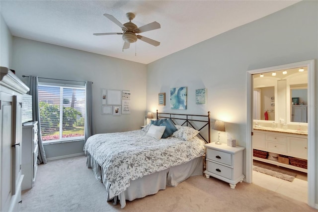 bedroom featuring ensuite bathroom, light colored carpet, a textured ceiling, and ceiling fan