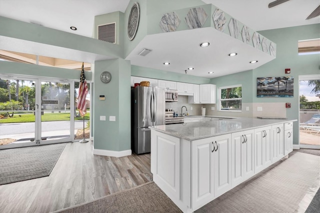 kitchen with sink, light wood-type flooring, appliances with stainless steel finishes, white cabinets, and backsplash