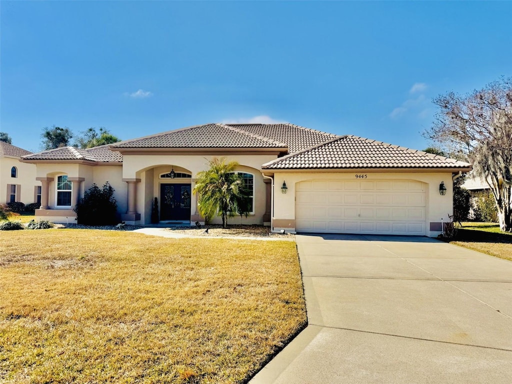 mediterranean / spanish-style home featuring a garage and a front lawn