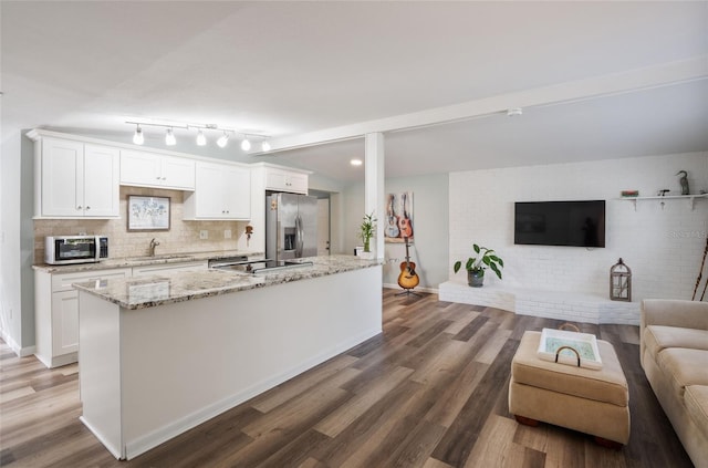 kitchen with sink, appliances with stainless steel finishes, white cabinets, a kitchen island, and dark hardwood / wood-style flooring