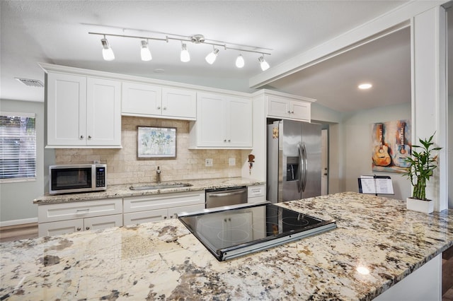 kitchen featuring sink, white cabinets, decorative backsplash, stainless steel appliances, and light stone countertops