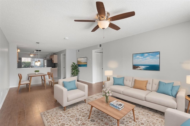 living room with ceiling fan, hardwood / wood-style floors, and a textured ceiling