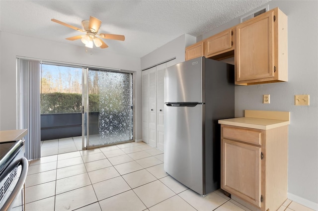 kitchen with appliances with stainless steel finishes, light tile patterned floors, a textured ceiling, and light brown cabinets