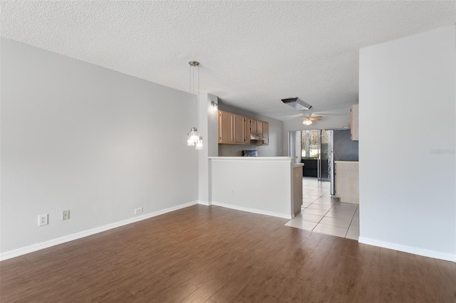 unfurnished living room with ceiling fan, light hardwood / wood-style floors, and a textured ceiling