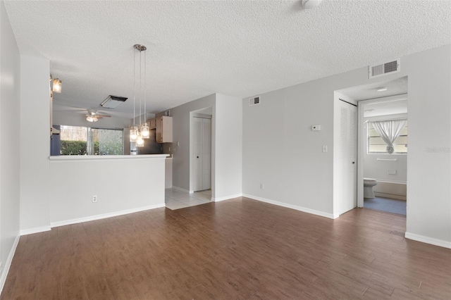 unfurnished living room with plenty of natural light, a textured ceiling, and light wood-type flooring