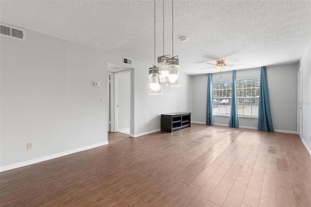 empty room with hardwood / wood-style flooring, a textured ceiling, and ceiling fan