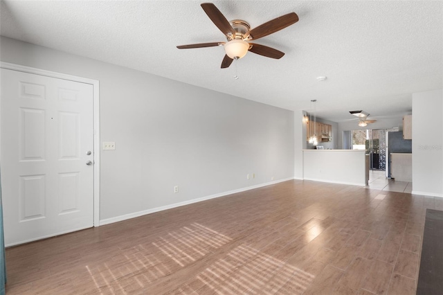 unfurnished living room with ceiling fan, hardwood / wood-style flooring, and a textured ceiling