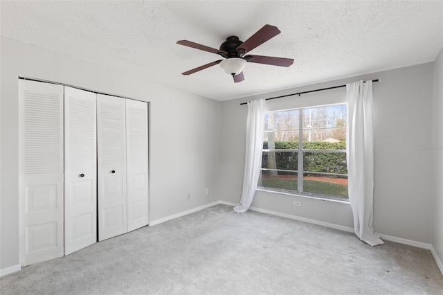 unfurnished bedroom featuring ceiling fan, light carpet, a textured ceiling, and a closet