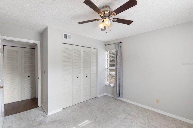 unfurnished bedroom with ceiling fan, light carpet, a textured ceiling, and a closet