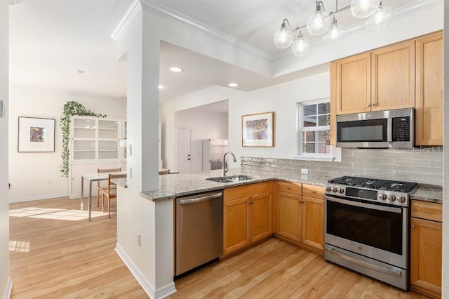 kitchen featuring light stone countertops, appliances with stainless steel finishes, sink, and crown molding