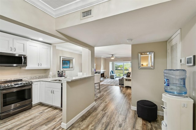 kitchen with white cabinetry, ornamental molding, light stone countertops, and appliances with stainless steel finishes