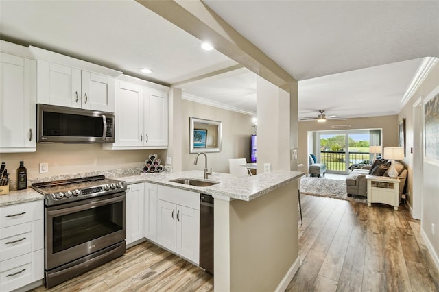 kitchen with stainless steel appliances, white cabinetry, sink, and kitchen peninsula