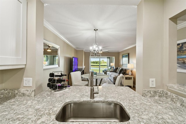 kitchen with sink, ornamental molding, and light stone countertops