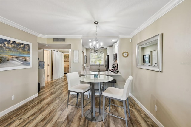 dining area featuring crown molding, sink, hardwood / wood-style floors, and an inviting chandelier