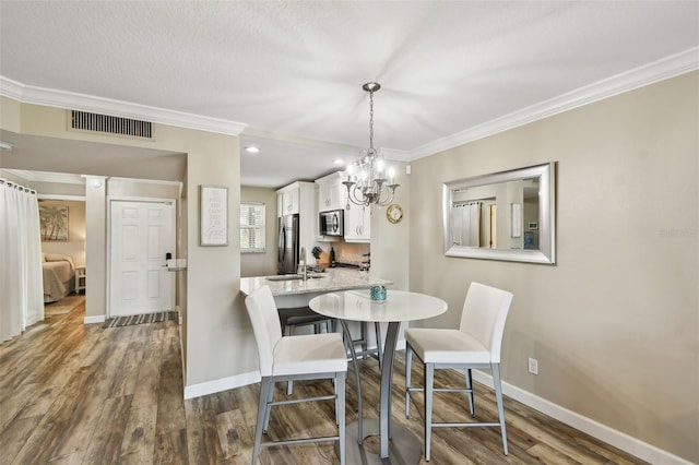 dining area featuring a notable chandelier, ornamental molding, dark hardwood / wood-style floors, and a textured ceiling